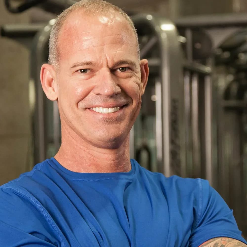 Craig Chapin smiling, close up, in a blue training shirt on the gym floor