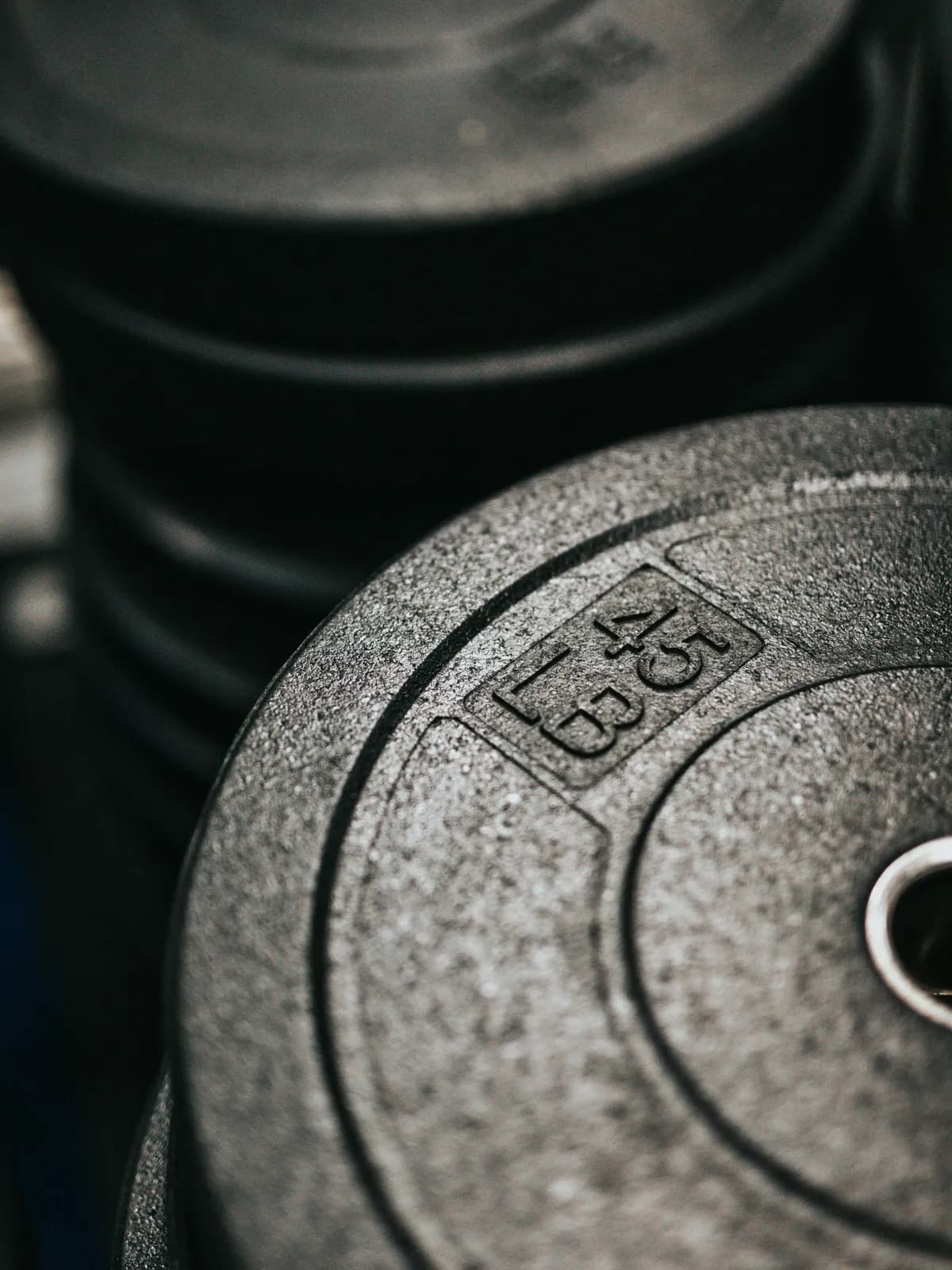 A stack of weight plates in a gym, the nearest one a 45-pound plate with the weight cast into its face